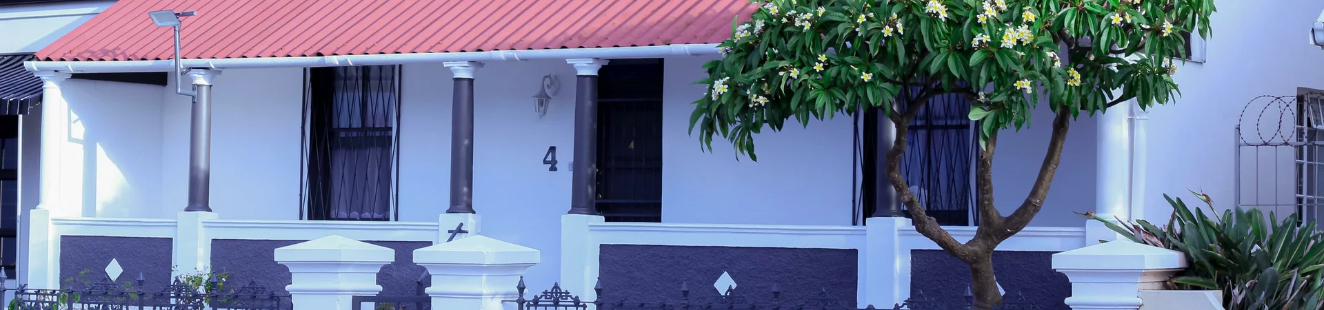A white house featuring a striking red roof, set against a clear blue sky, showcasing a charming architectural design.